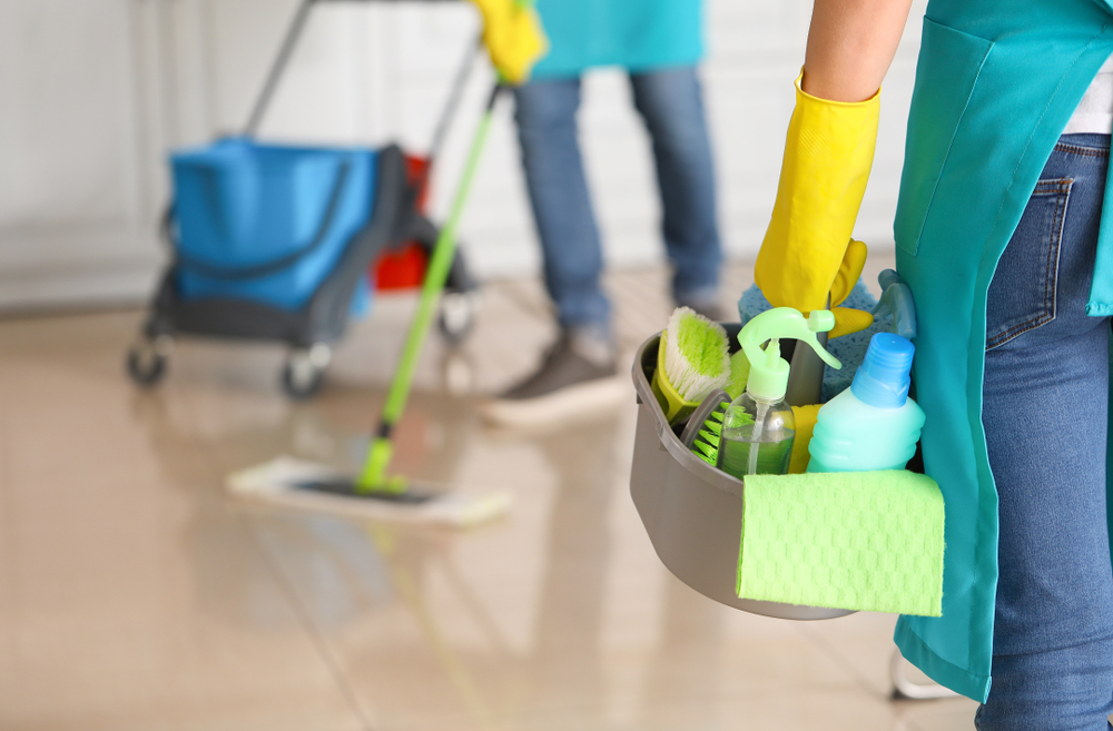 Cleaner mopping a floor beside a cleaning trolley