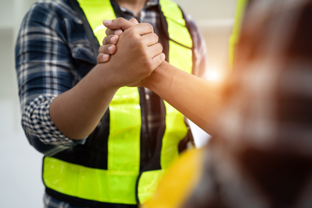 Two workers in hi-vis shaking hands