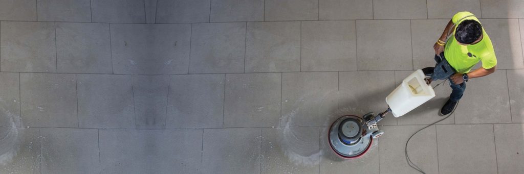 Cleaner polishing a floor with a scrubber machine