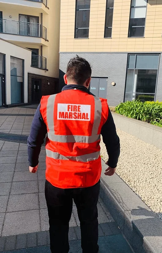 Fire marshal in a red vest walking outside a building