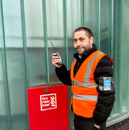 FCS Group fire marshal in hi-vis with a radio beside a dry riser inlet