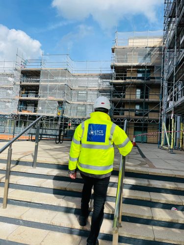 FCS Group security officer patrolling a construction site with scaffolding
